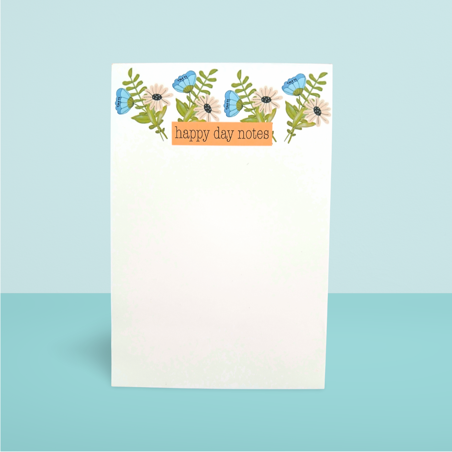 Notepad with floral design and 'happy day notes' text on a light blue background