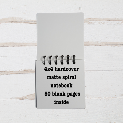Gray 4x4 hardcover matte spiral notebook with text on a white wooden background