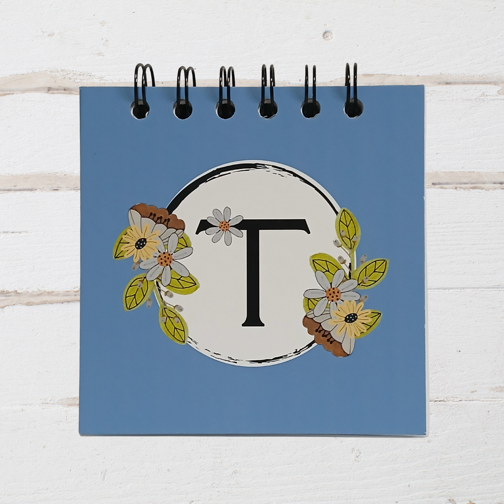 Small notebook with a floral design and letter 'T' on a blue background