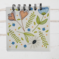 Notebook with floral illustrations on a white wooden surface