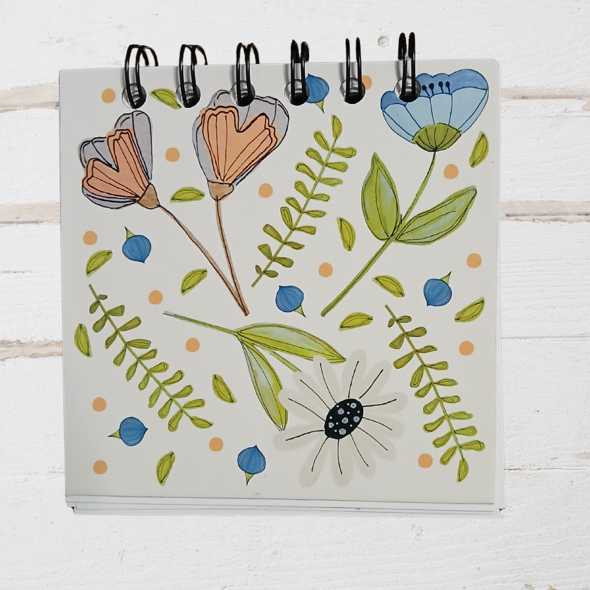 Notebook with floral illustrations on a white wooden surface