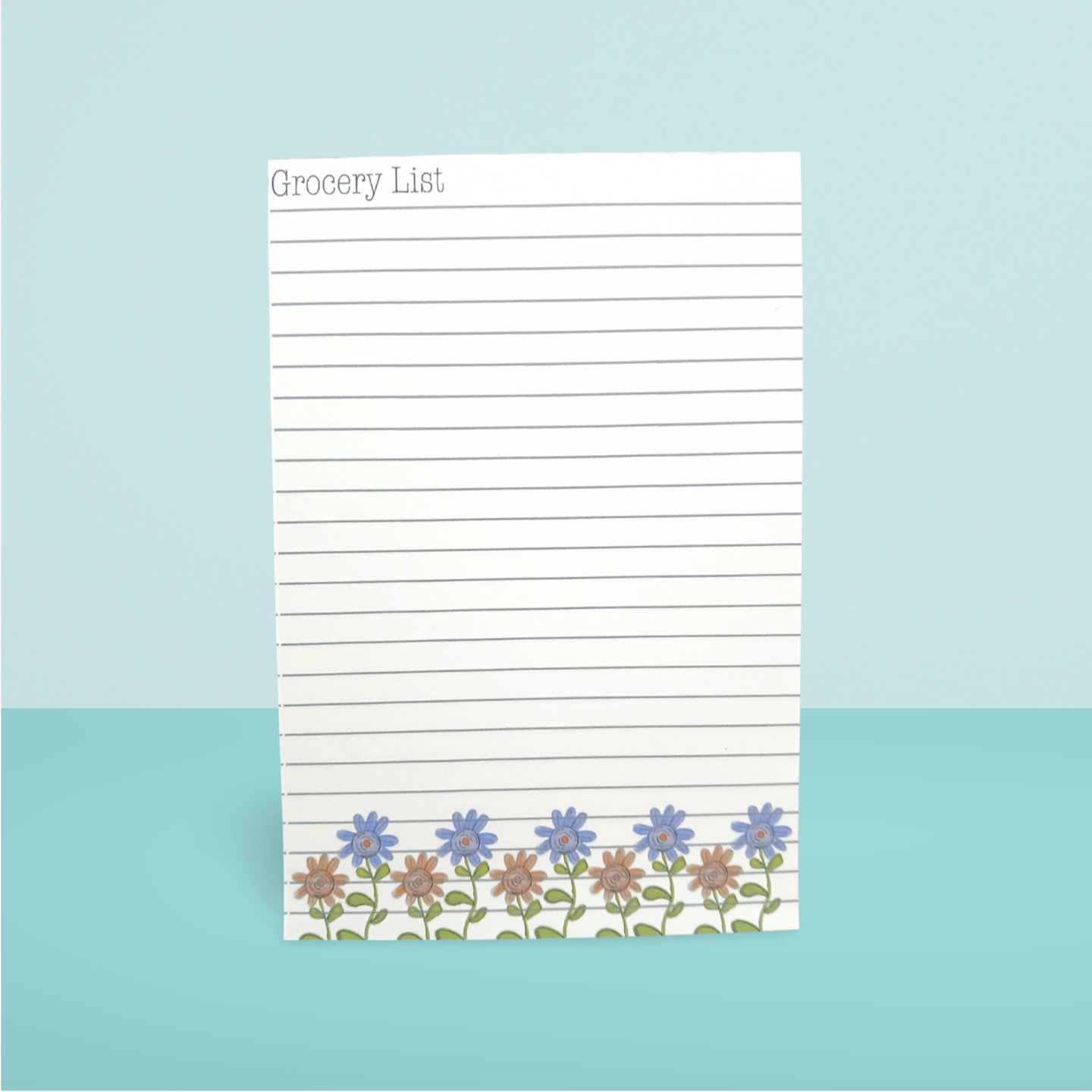 Grocery list notepad with floral design on a light blue background