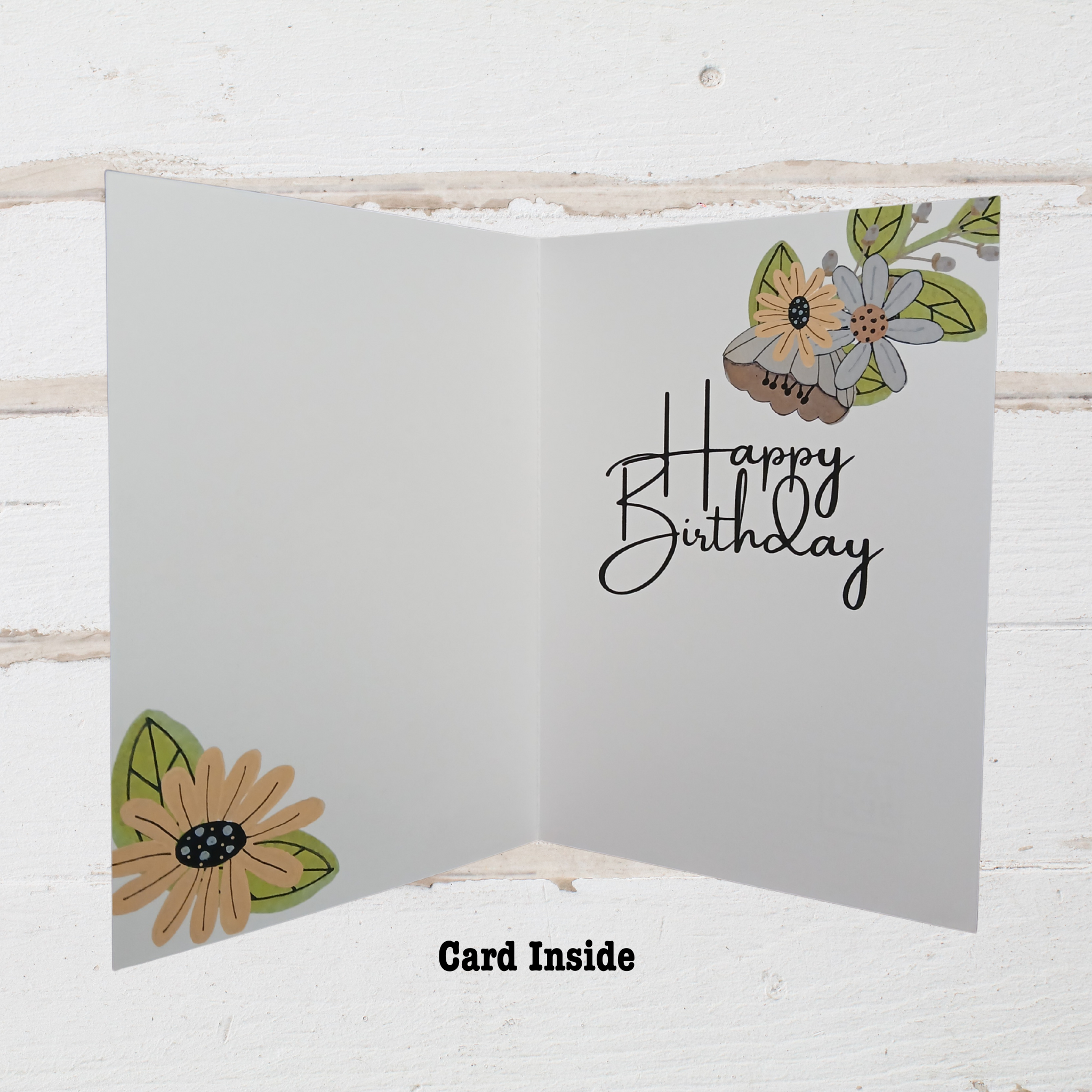 Open birthday card with floral designs and 'Happy Birthday' text on a wooden surface.