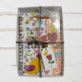 Set of stationery items including a notebook, cards, and a tag with floral and bird designs, tied together.