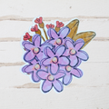 Sticker with purple flowers and pink buds on a light wooden surface