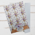 Floral patterned card with a teacup design on a wooden surface