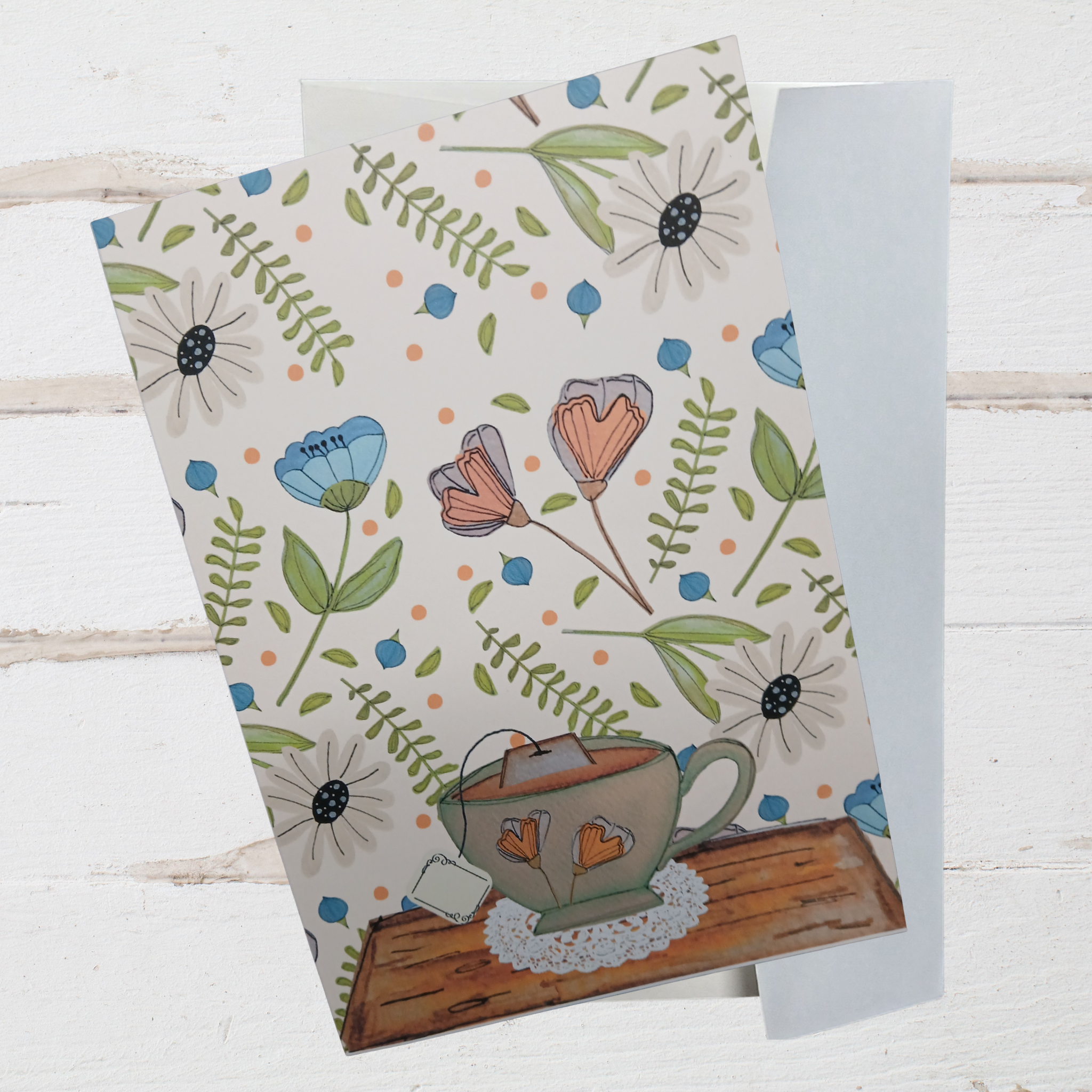 Notebook with floral design and teacup illustration on a wooden surface