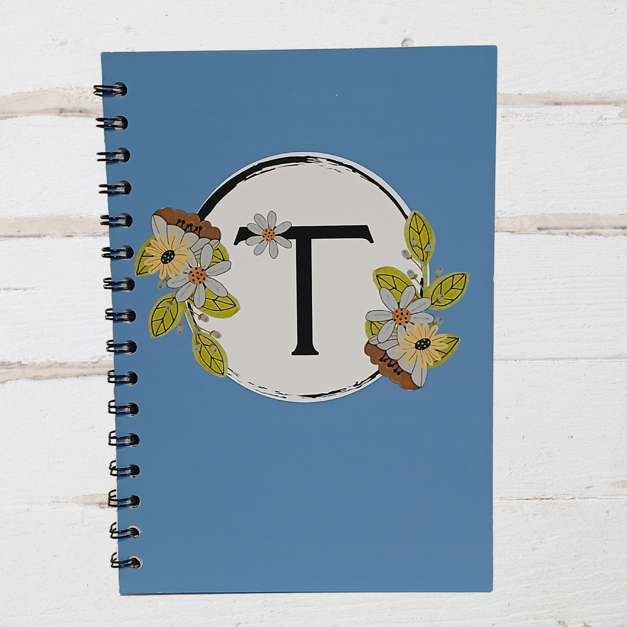 Notebook with floral design and letter 'T' on a blue cover