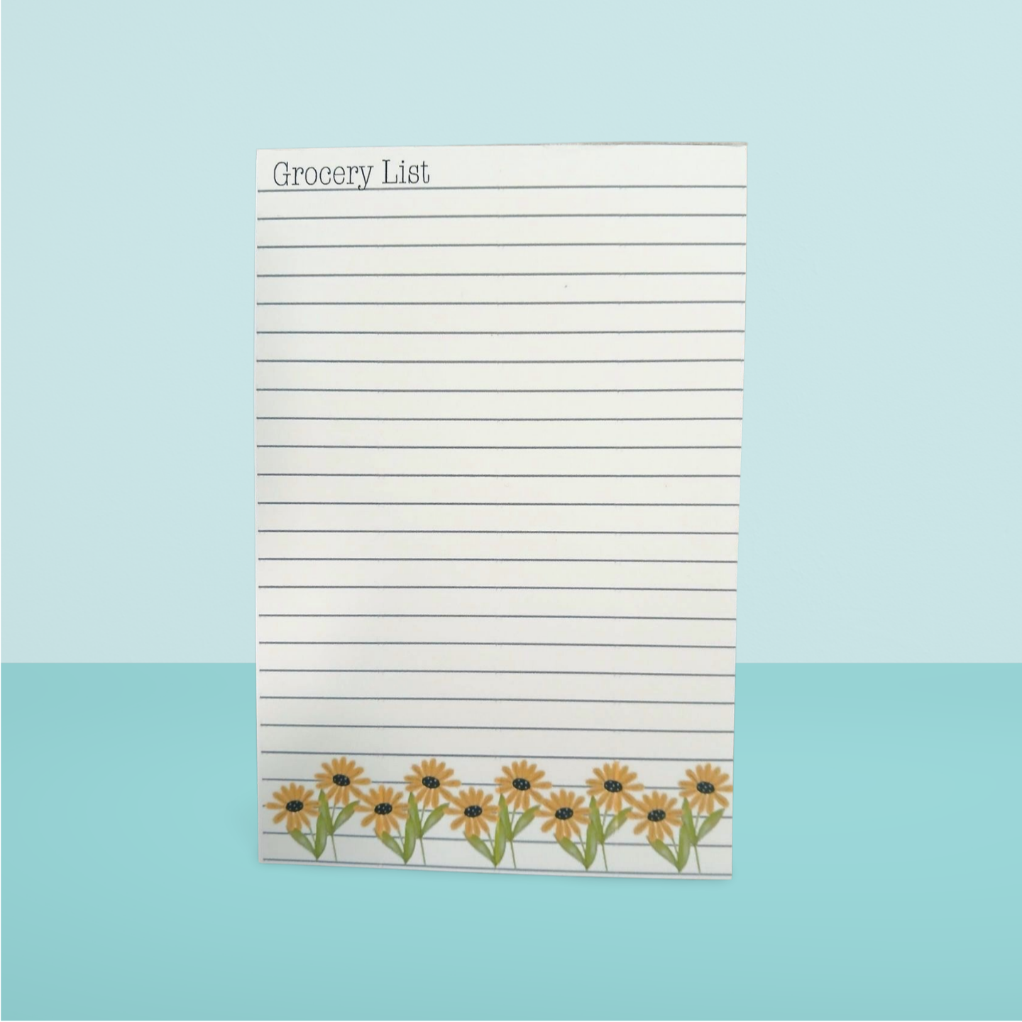 Notepad with 'Grocery List' text and sunflower design on a light blue background