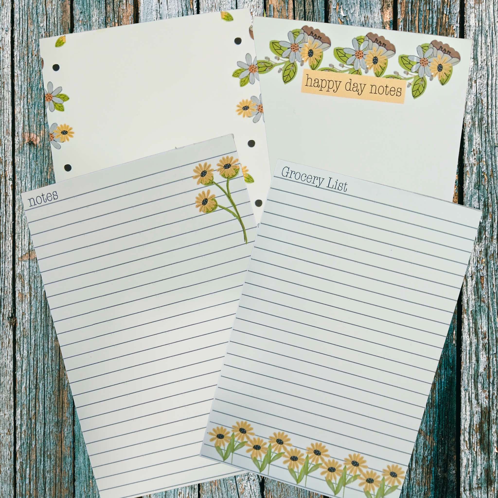 Four floral themed notepads on  a wooden background