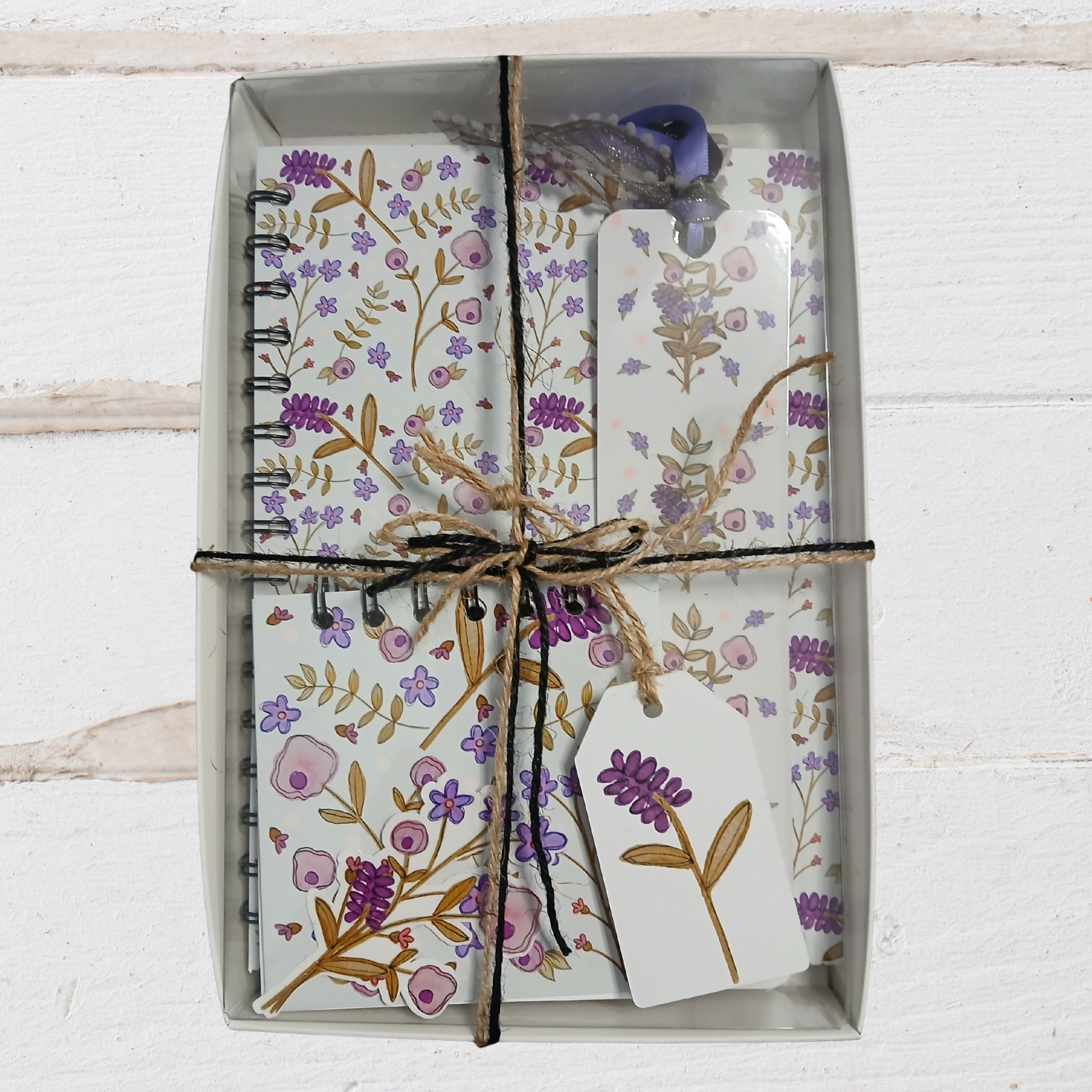 Floral notebook and card set with decorative ribbon on a white wooden surface