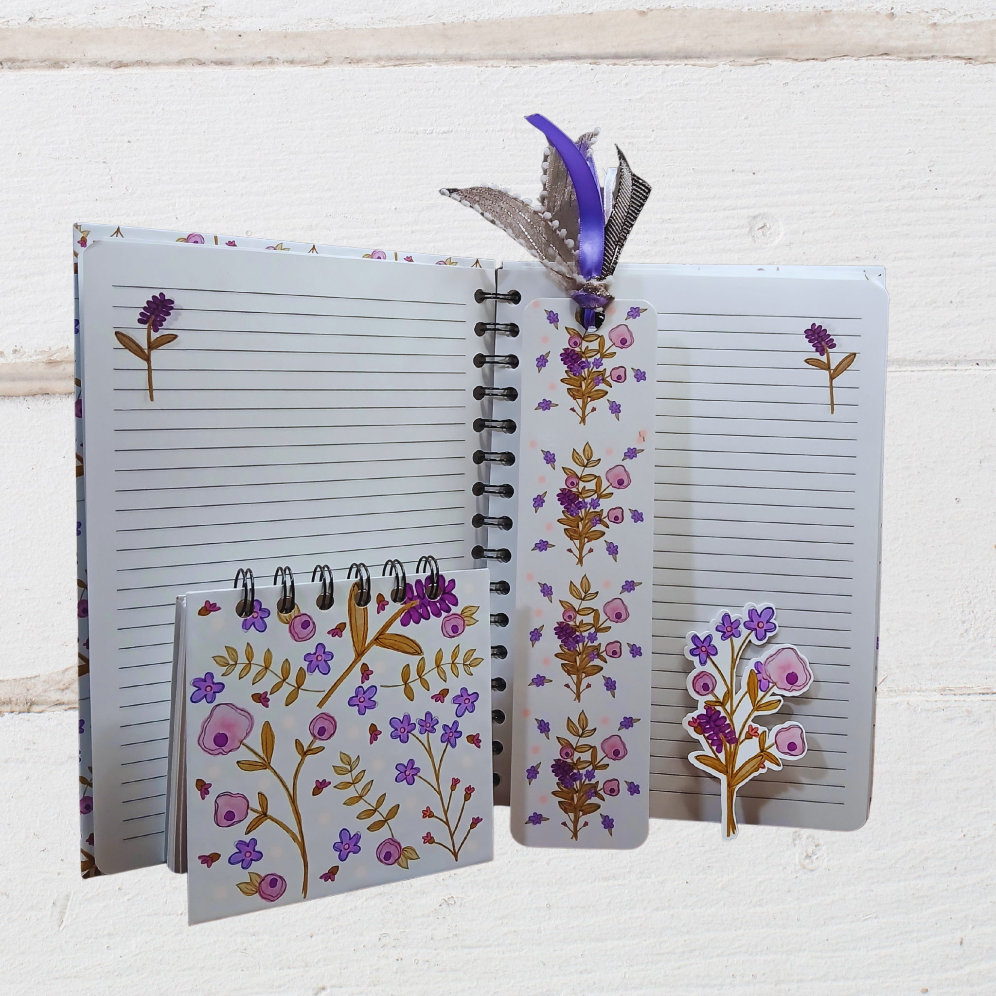 Open notebook with floral design on cover and pages, featuring a bookmark and pen holder.