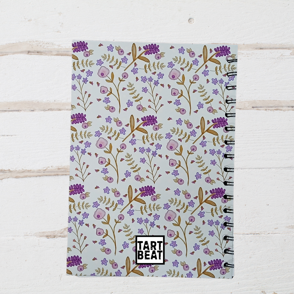 Notebook with floral pattern and 'Tart Beat' branding on a light wooden surface