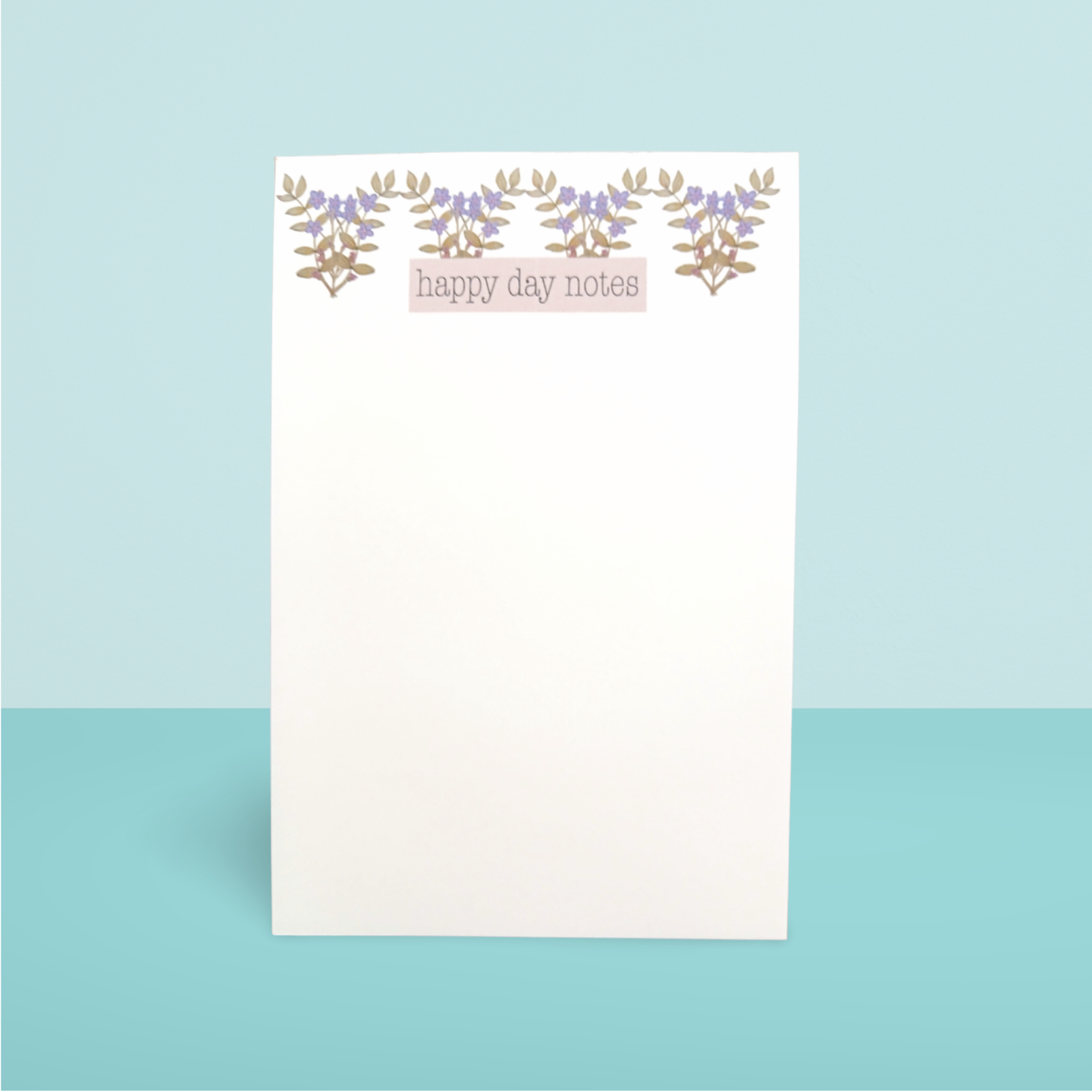 Notepad with 'happy day notes' text and floral design on a light blue background