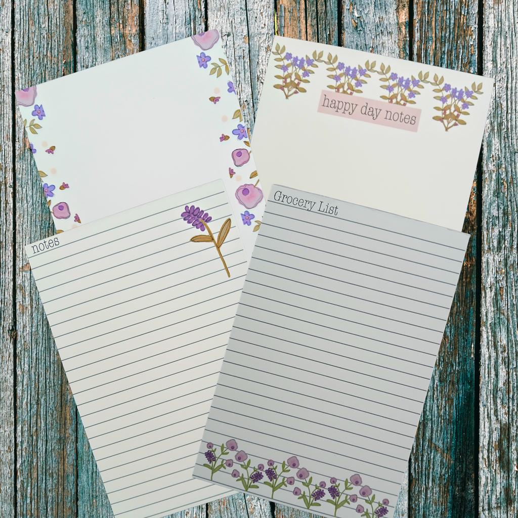 Four floral decorated notepads on a wooden background