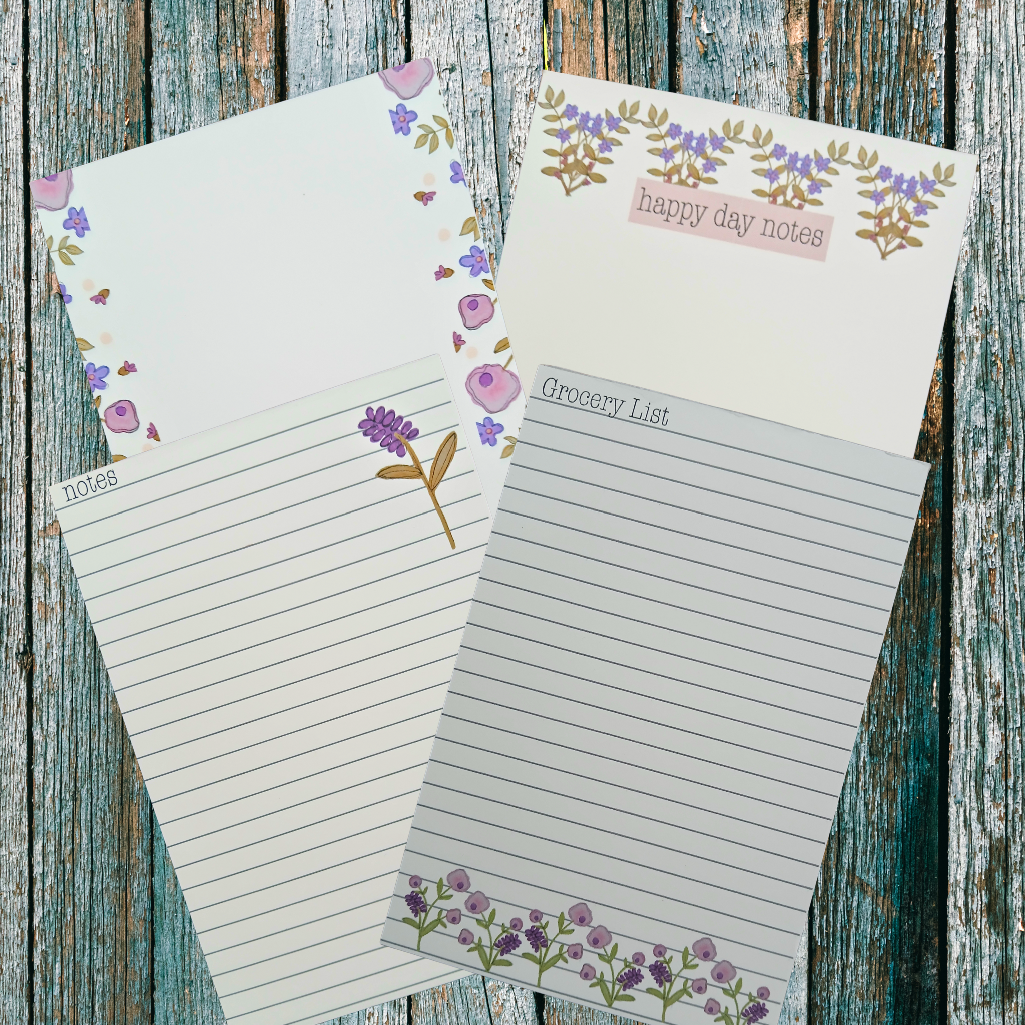 Four floral decorated notepads on a wooden background