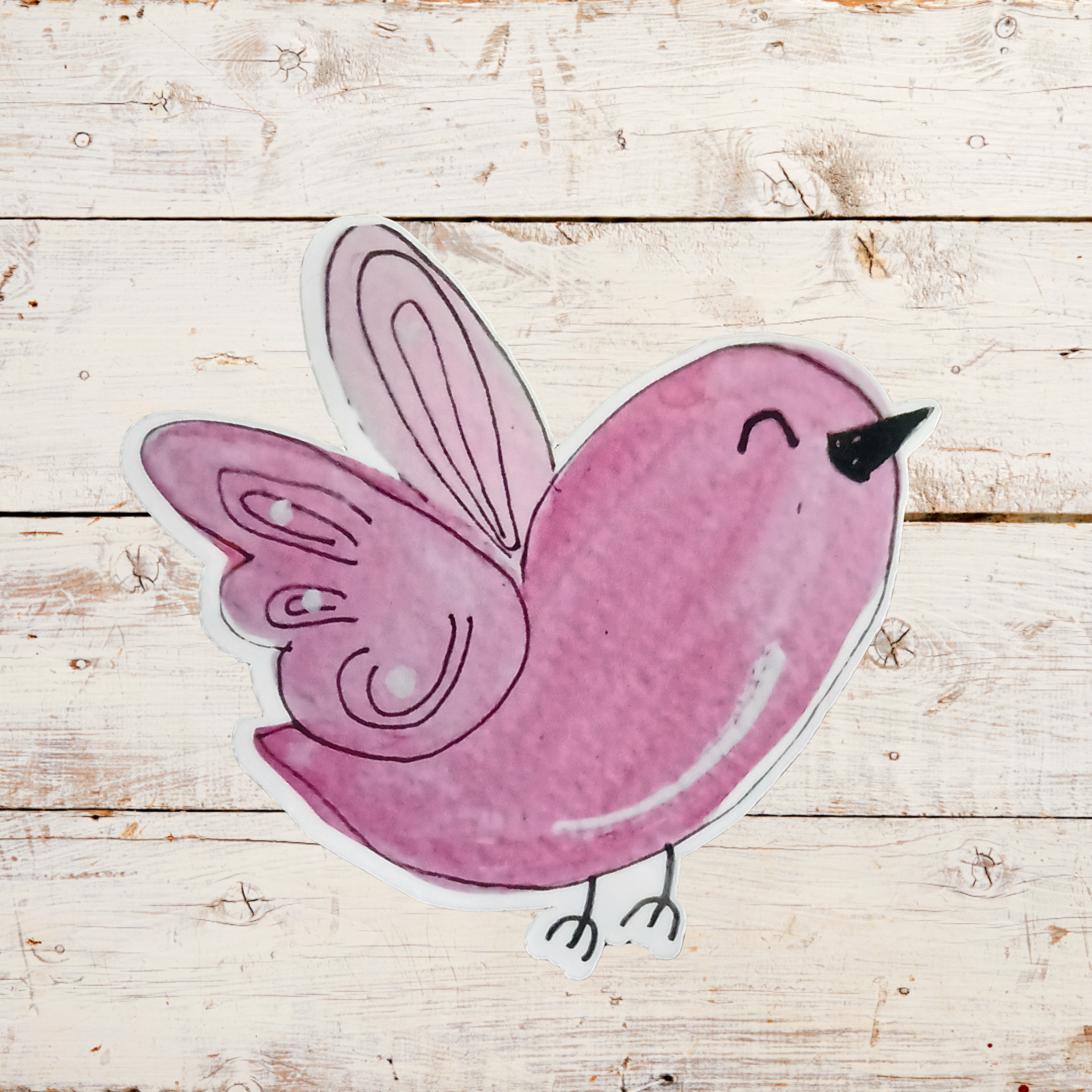 Pink bird-shaped sticker on a wooden surface