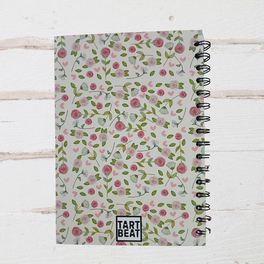 Notebook with floral pattern and 'Tart Beat' branding on a light wooden surface