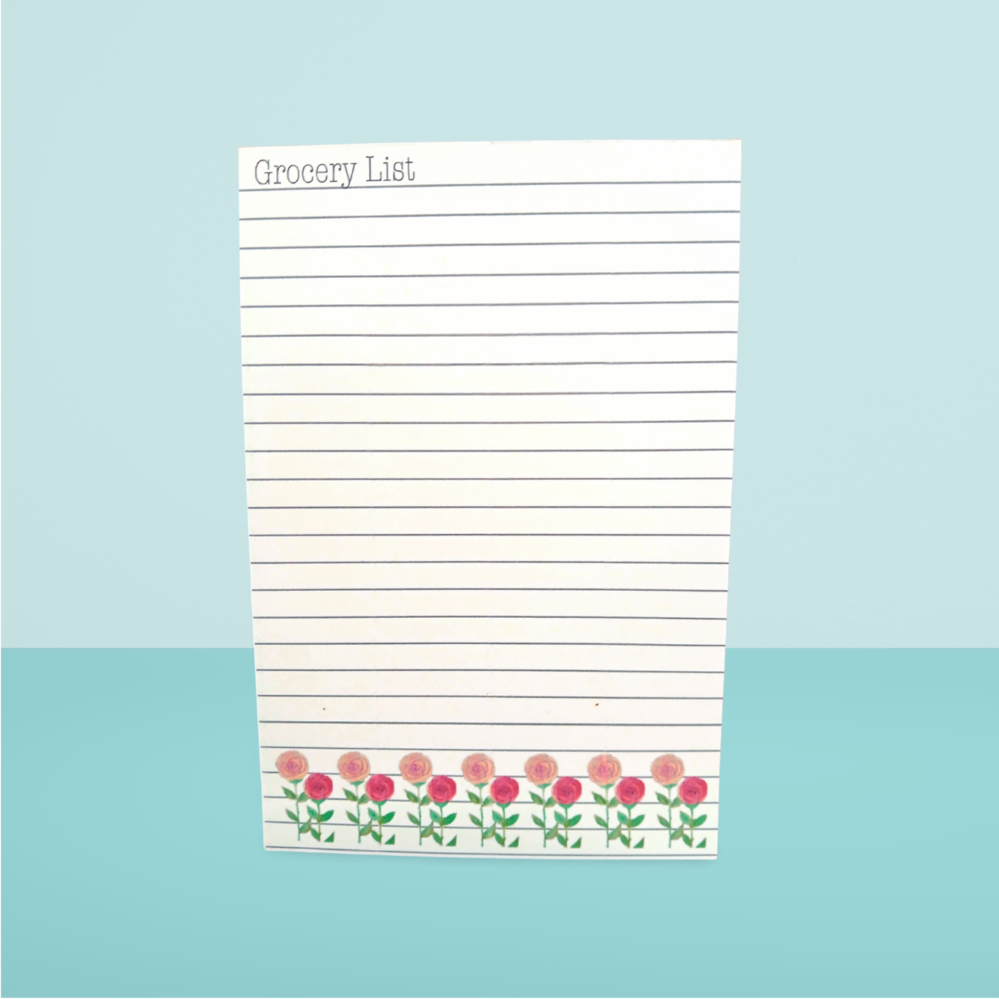 Grocery list notepad with floral design on a light blue background
