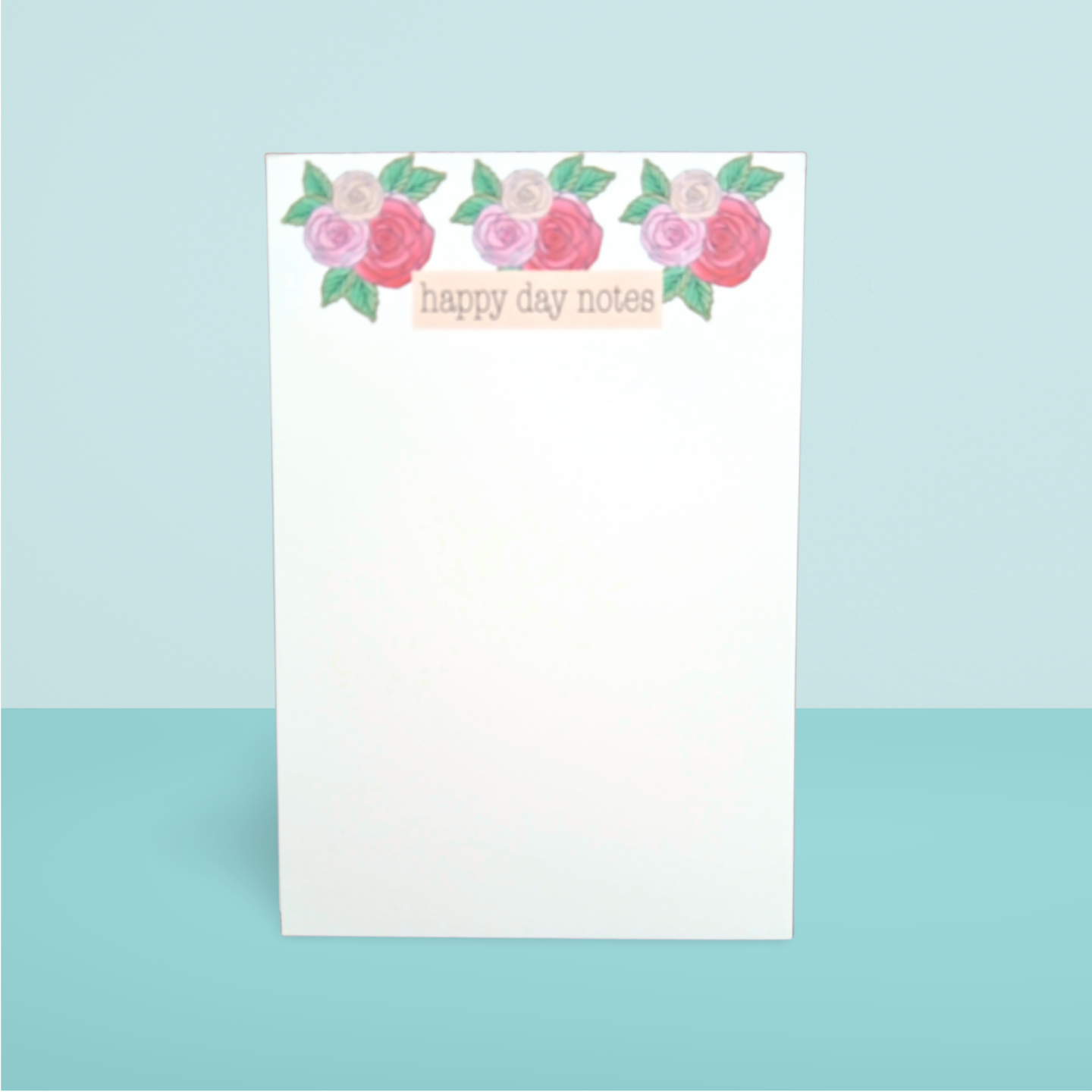Notepad with floral design and 'happy day notes' text on a light blue background