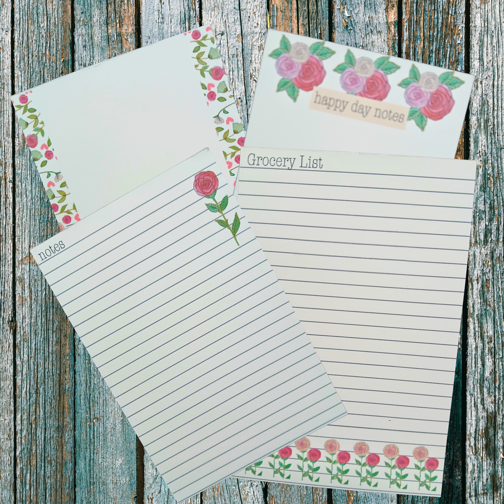four floral decorated notepads on a wooden background