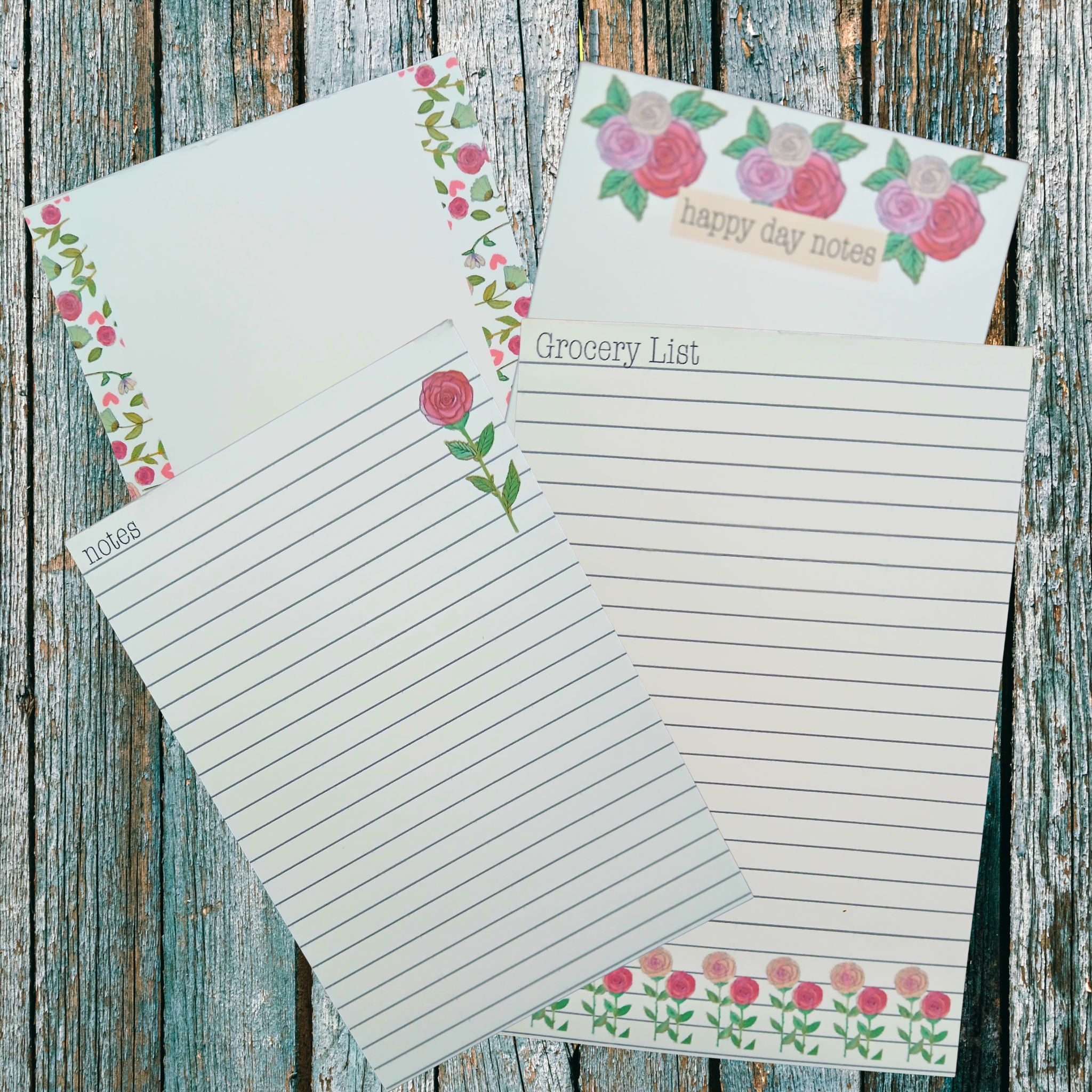 four floral decorated notepads on a wooden background