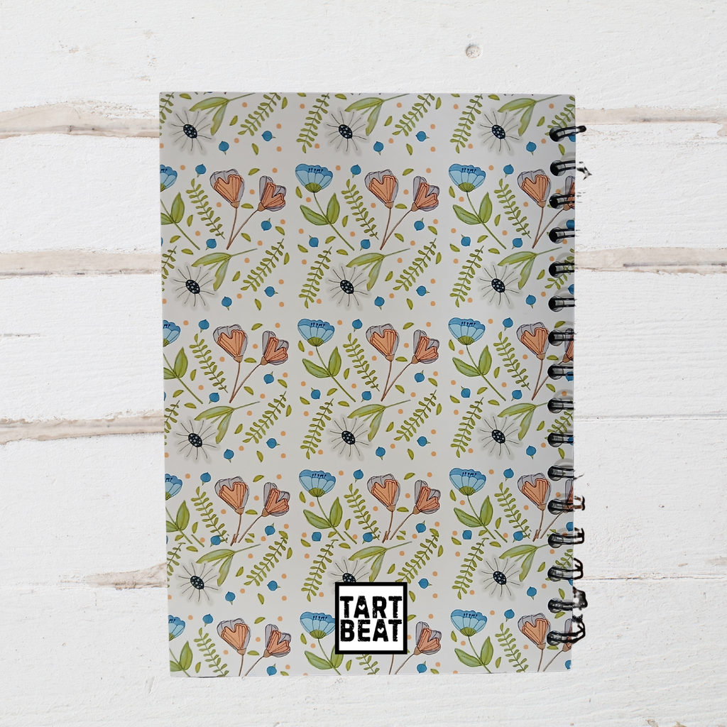 Notebook with floral pattern and 'Tart Beat' branding on a wooden surface
