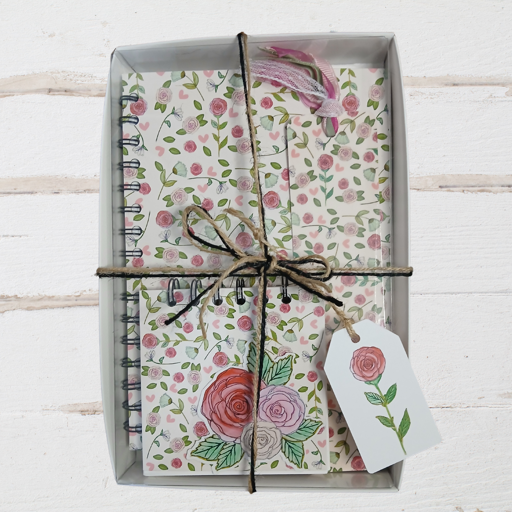 Floral notebook set with decorative paper and twine on a white wooden surface